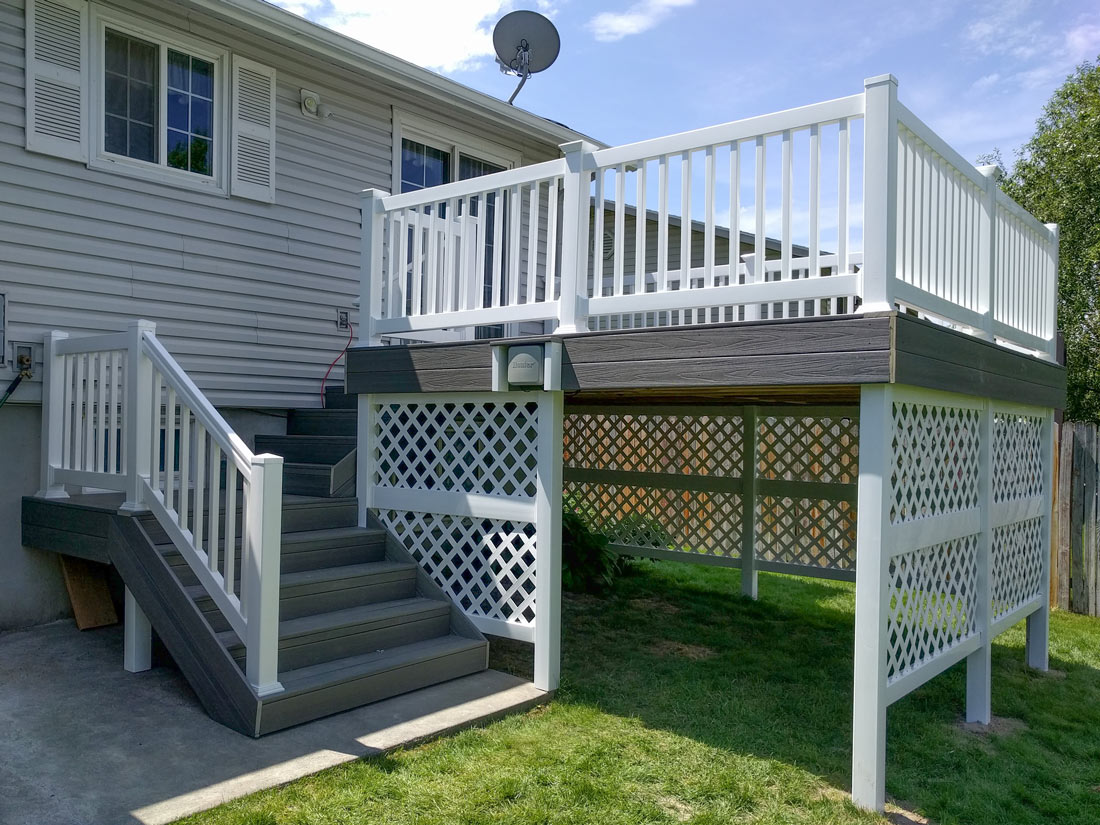 Achieve a clean, finished look for your backyard with a custom DeckPro LLC project. This raised grey composite deck features durable white vinyl railing and matching lattice skirting to beautifully enclose the under-deck area for a polished appearance.