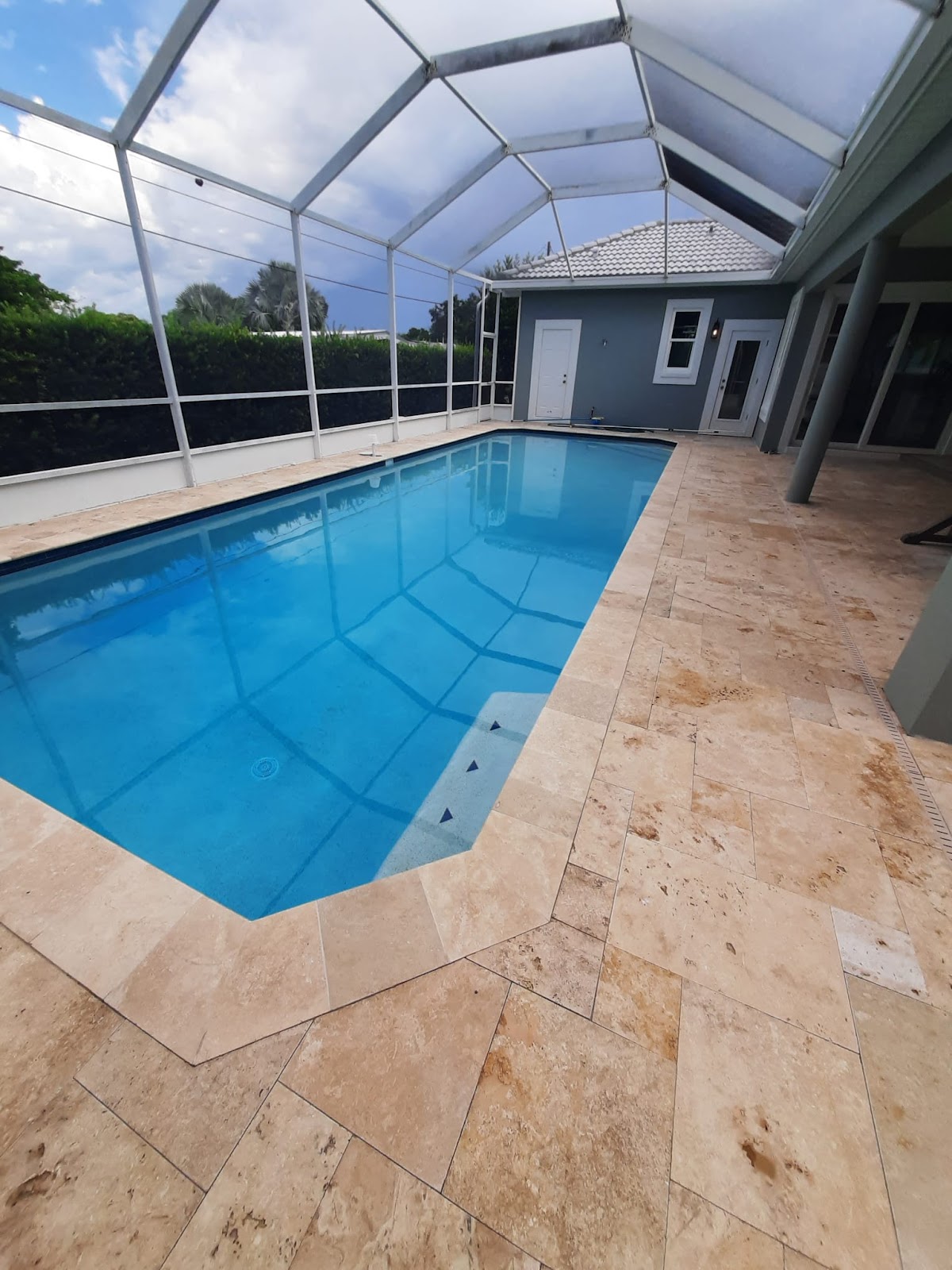 Screen-enclosed backyard swimming pool with clear blue water, light stone paver decking, and a covered residential patio.
Select 82 more words to run Humanizer.