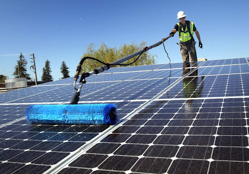 Professional solar panel cleaning on a large rooftop solar array, illustrating the type of specialized solar maintenance service available from SunWorx Solar Services in Arizona.