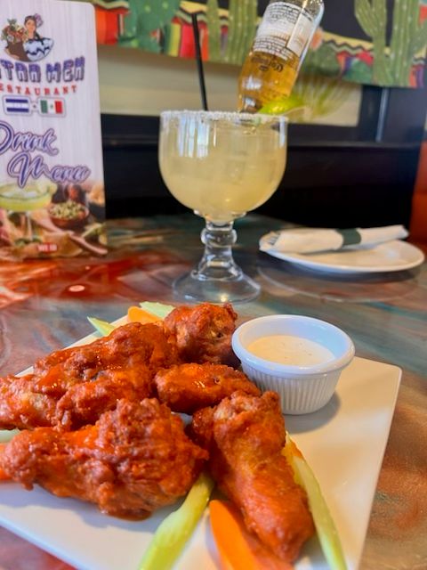 Crispy bone-in buffalo wings tossed in spicy sauce and served with fresh vegetables and dipping sauce at Catramex Restaurant.