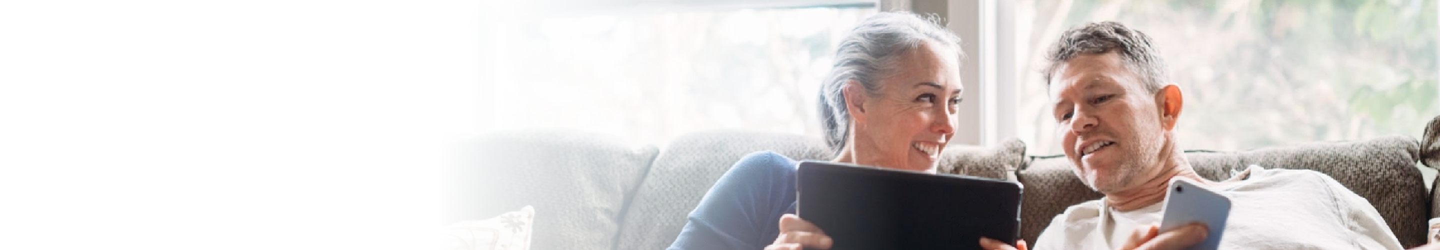 A couple on their couch looking at their devices.