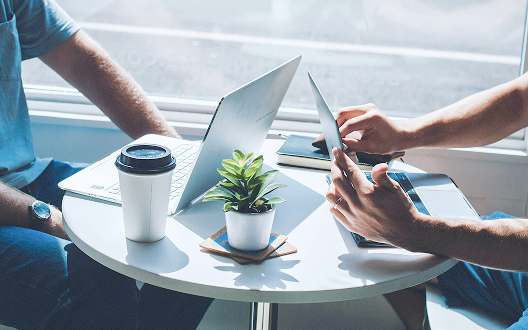 Close-up of two people working at a small round table.