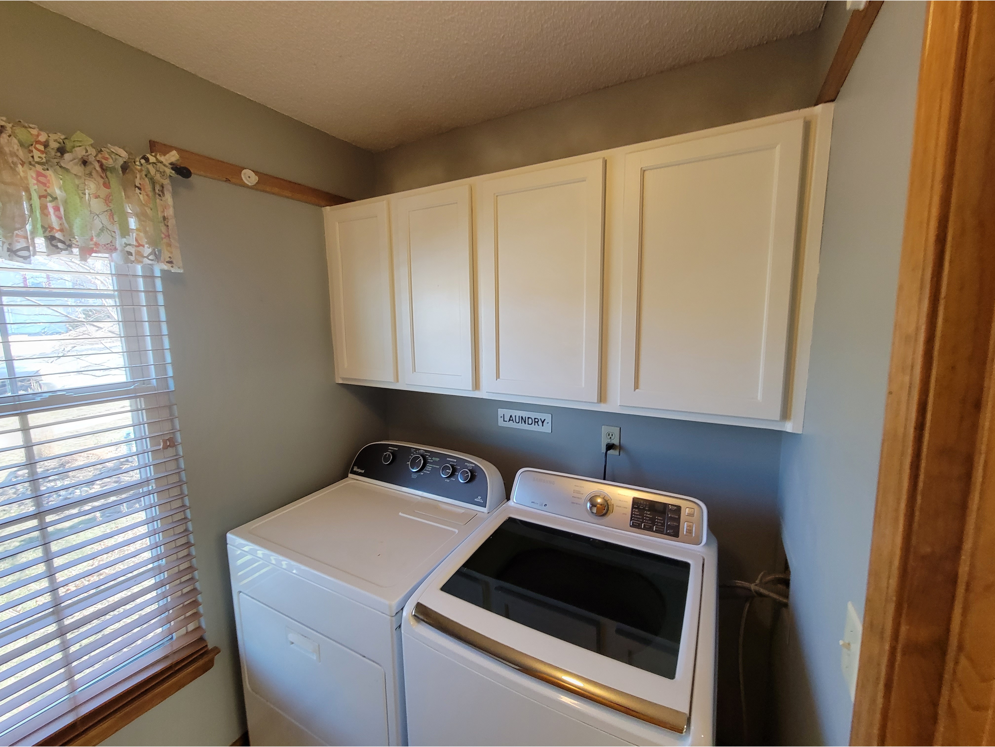 A laundry room featuring freshly painted white cabinets with a smooth, clean finish, providing a modern and updated look. Ideal for showcasing cabinet painting and refinishing services that enhance functionality and style in utility spaces.