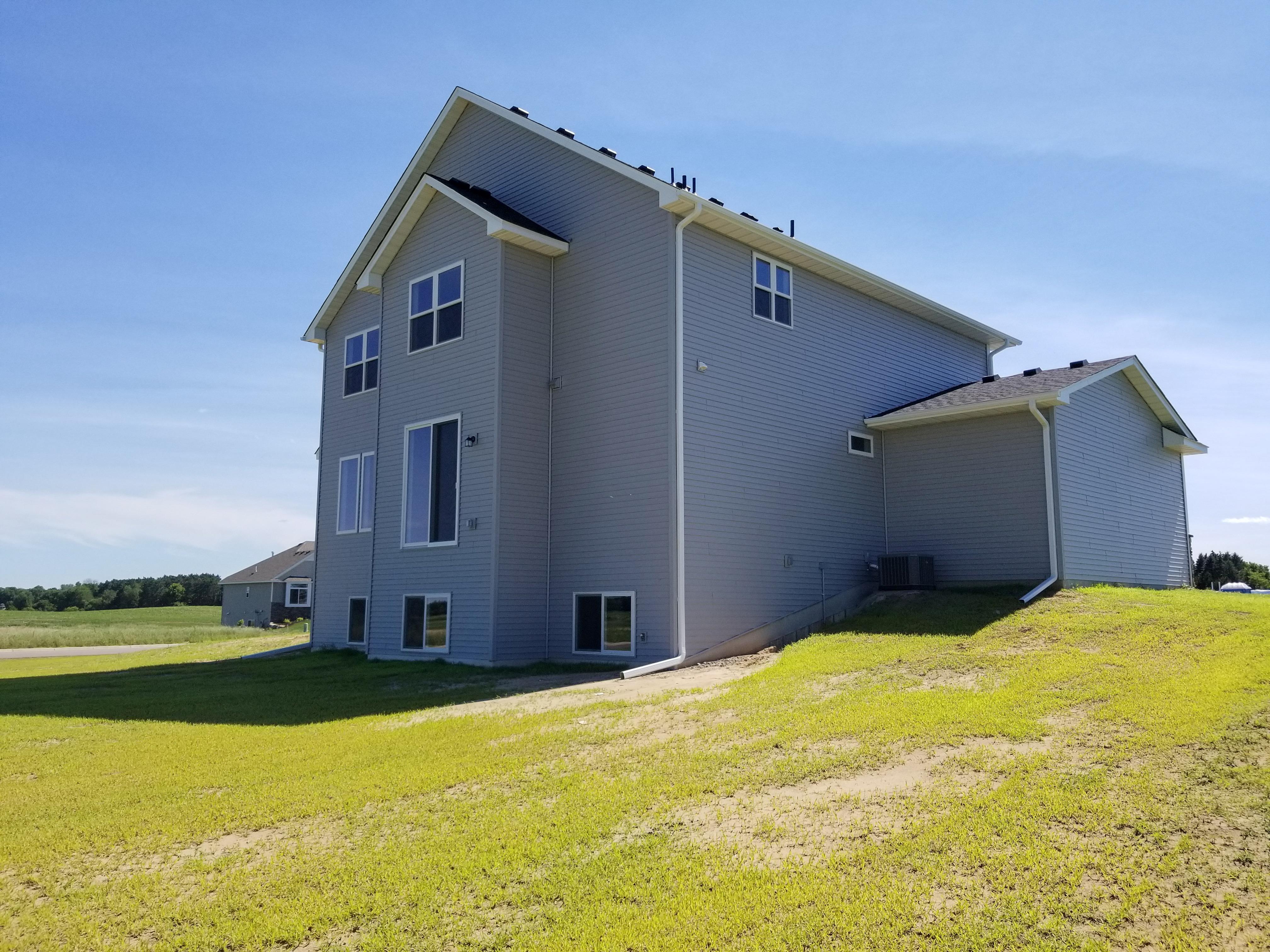 White seamless gutters and downspout system installed on the side of a two-story home by Ultimate Gutter Solutions.