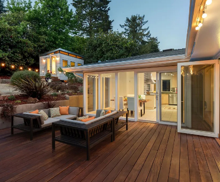 Evening shot of a custom dark wood-grain composite deck complete with outdoor lounge seating, string 