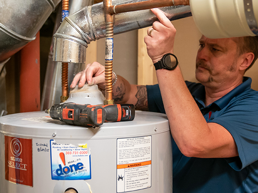 A Done plumber fixing a water heater in a home