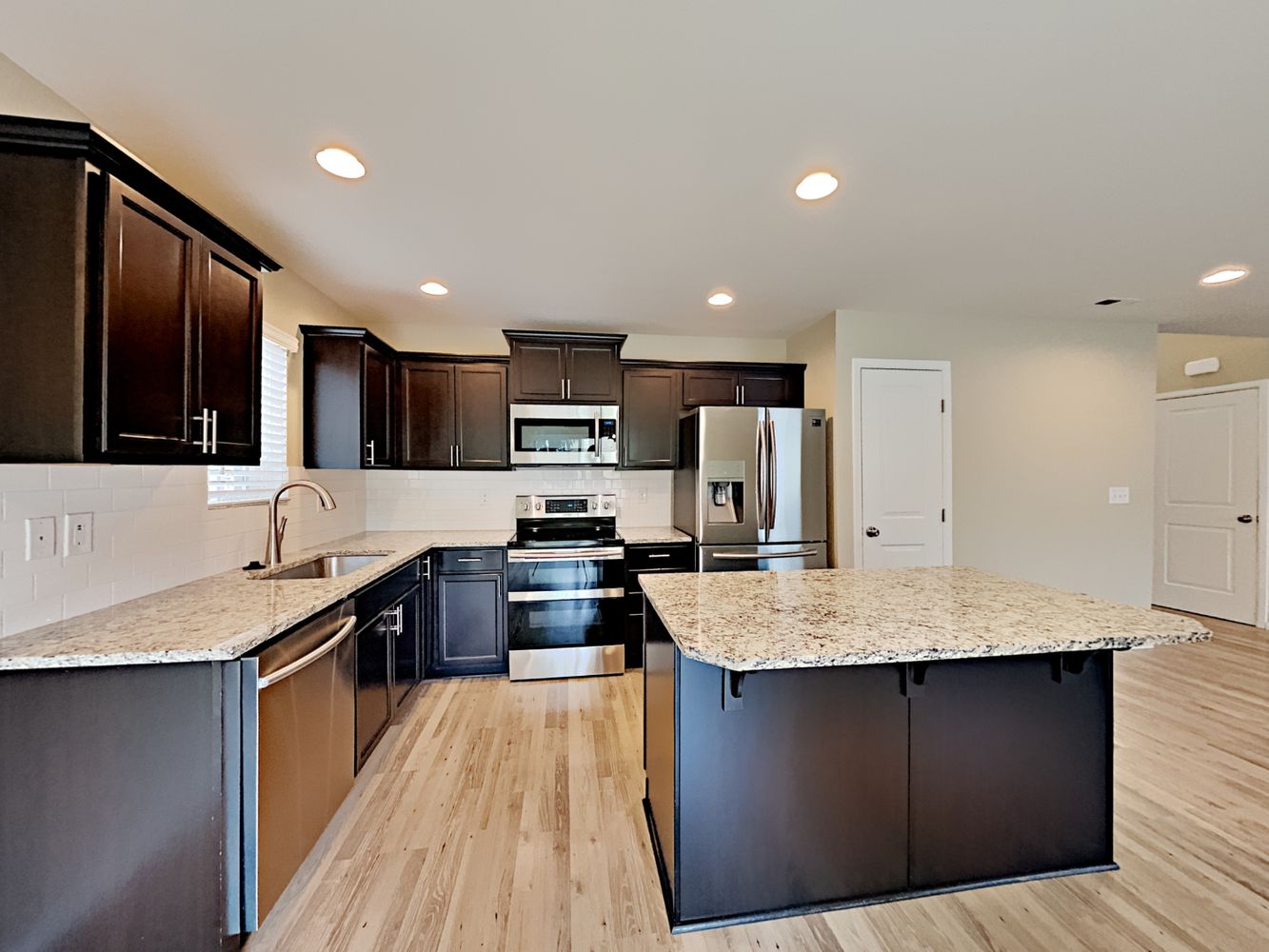 Open floorplan kitchen with granite countertops and stainless-steel appliances at Invitation Homes Seattle.