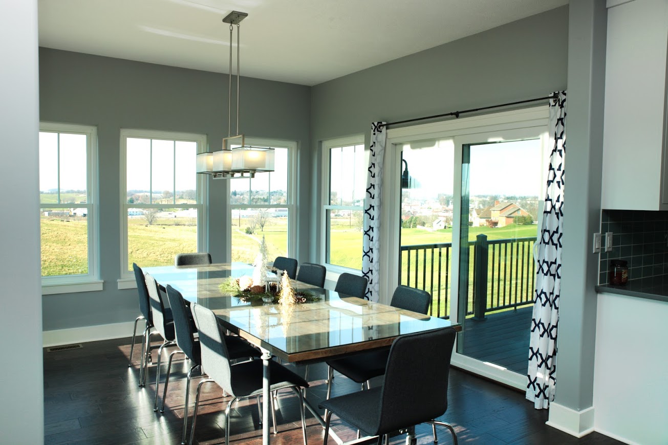 The EcoTek 3200 Series Double-Hung Windows in this dining room provide expansive views and abundant natural light, creating a bright and open feel. Paired with modern decor and a sliding patio door, these windows enhance the room's connection to outdoor spaces, blending interior comfort with the beauty of the outdoors.