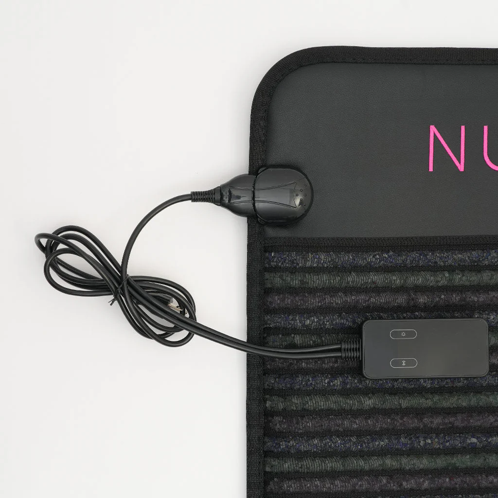 A close-up shot of an infrared PEMF mat, showing its textured surface, power cord, and control unit. The mat is black with a dark gray and blue striped pattern. A pink logo with the letters "NU" is visible on the upper right portion of the mat.