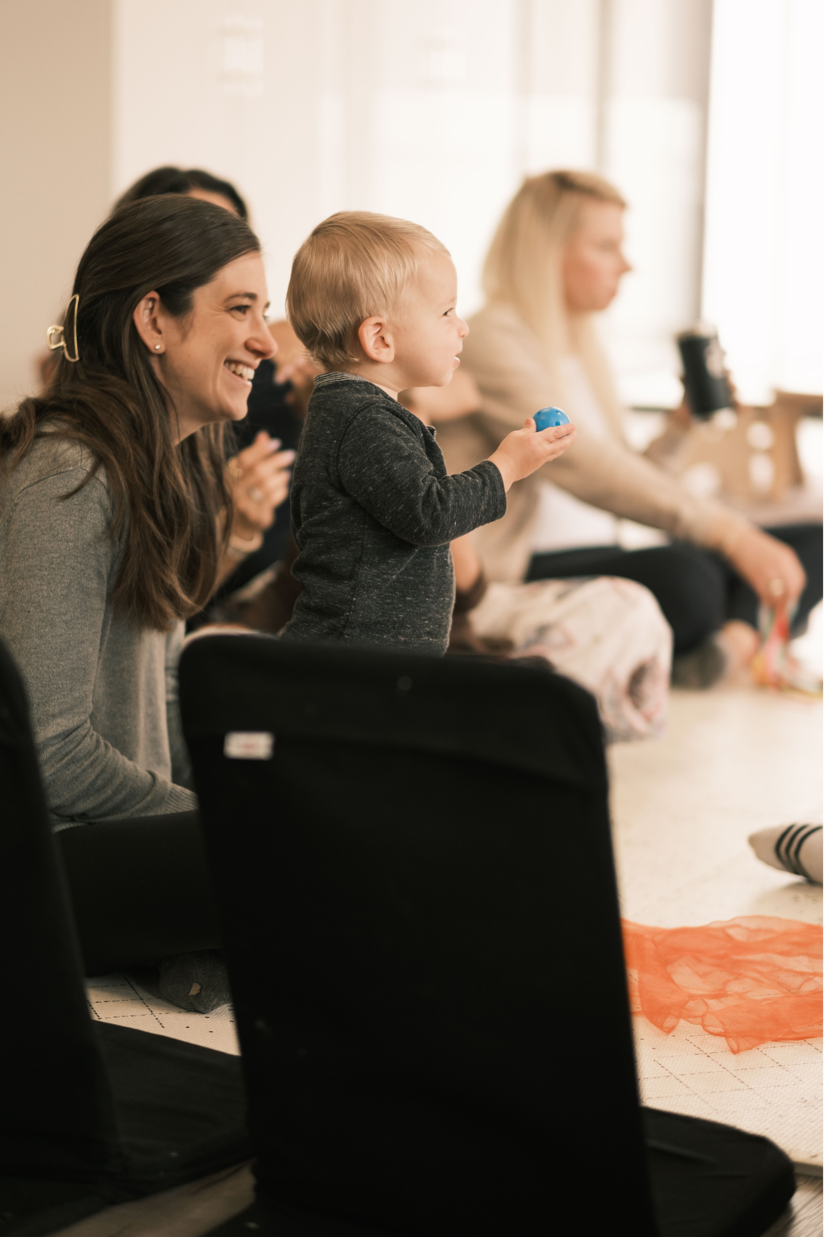 Moms and their babies sit at a table laughing and learning