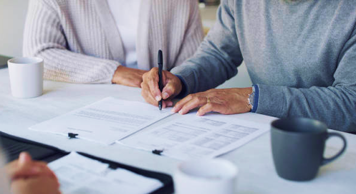 Close-up shot of client filling out paperwork during a meeting with their advisor.