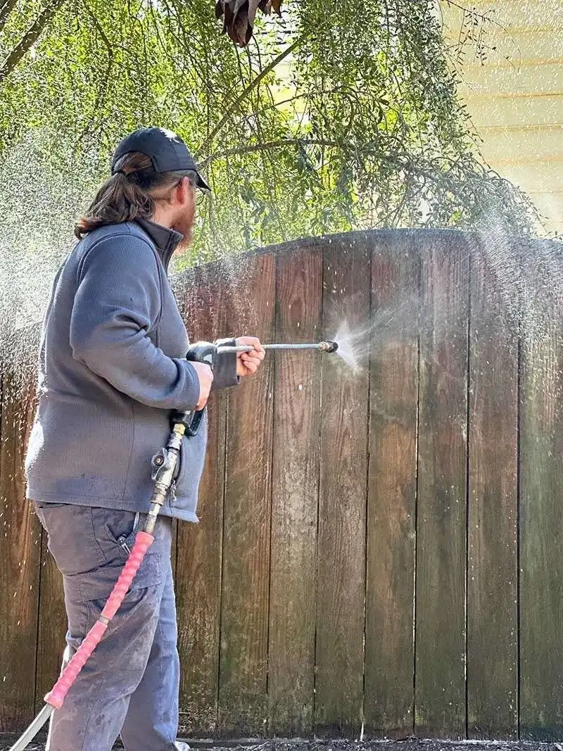 Professional pressure washing service removing dirt and buildup from fence.