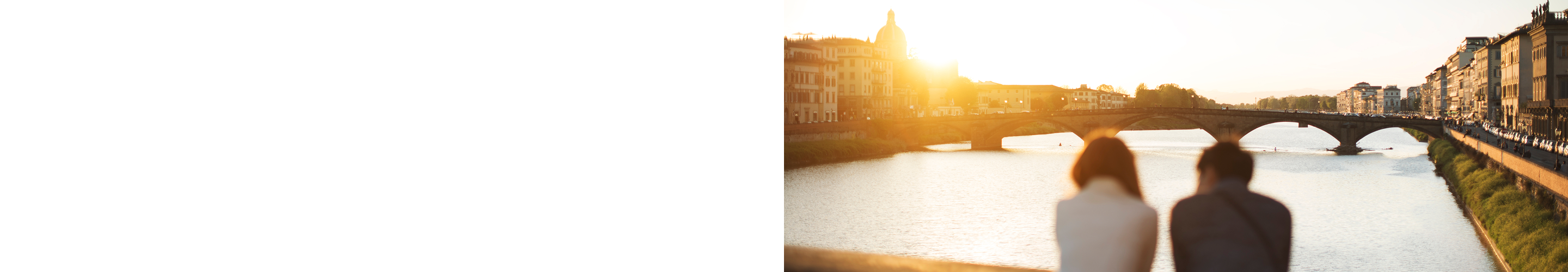 A couple enjoying a scenic sunset view of a bridge over a river.