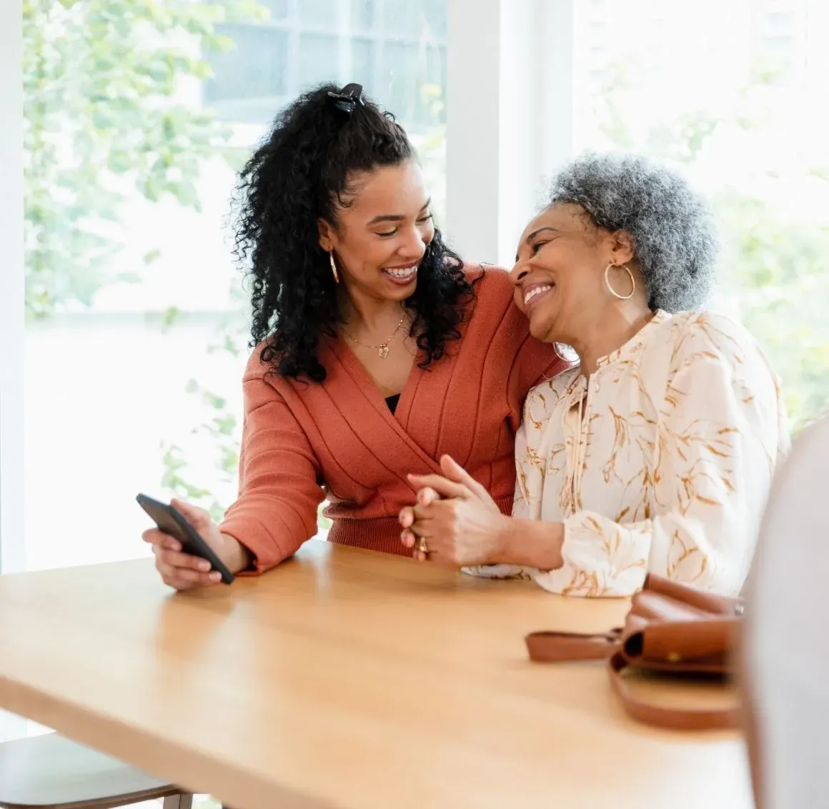 Caregiver Chatting with Senior
A warm moment shared between a caregiver and her client as they laugh together over something on her phone. This joyful connection reflects the genuine relationships caregivers build &mdash; going beyond assistance to become trusted companions in everyday life.