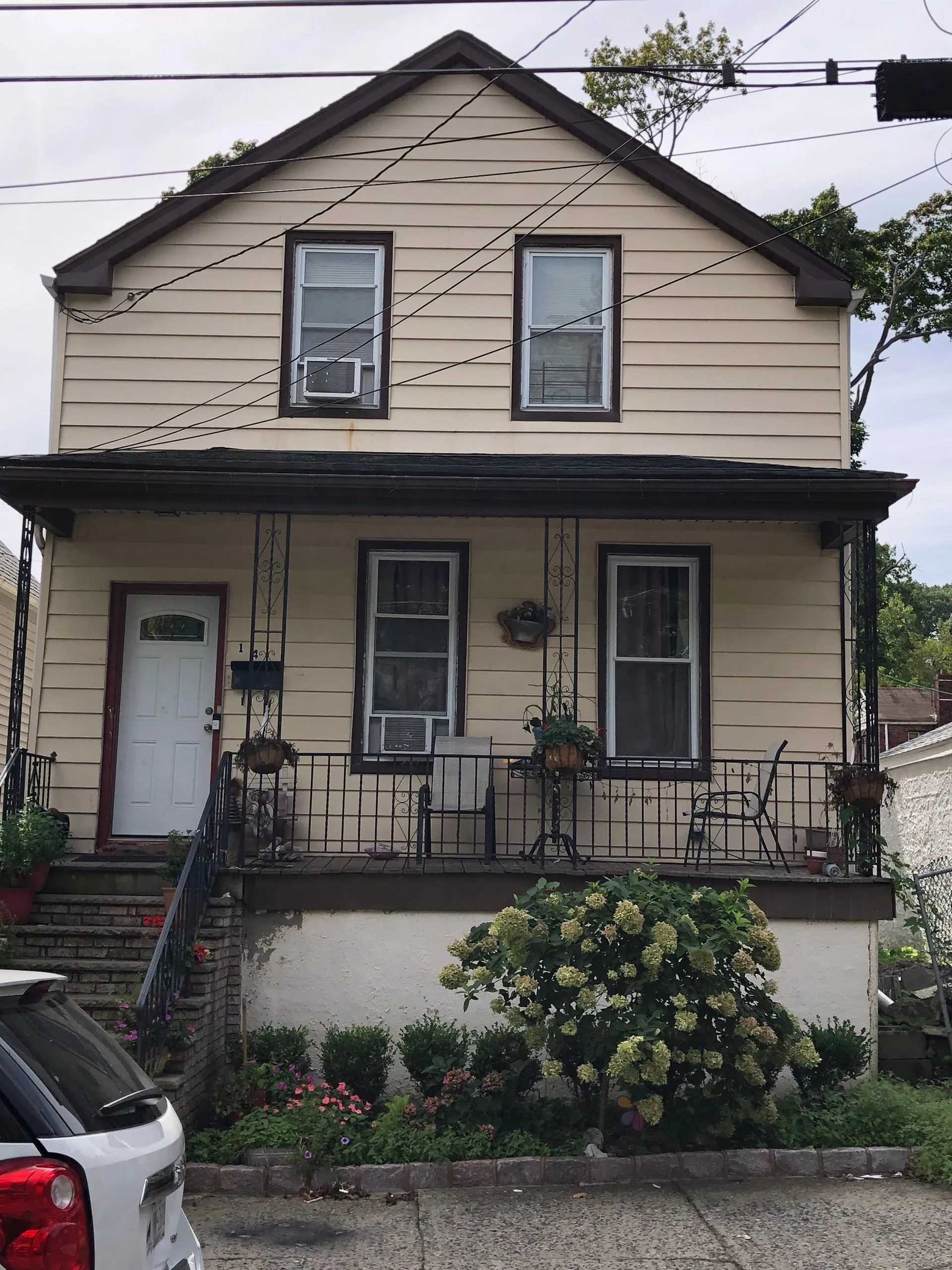 Two-story home featuring newly installed light-colored siding with contrasting trim. The exterior renovation improves curb appeal, weather protection, energy efficiency, and the overall appearance of the property.