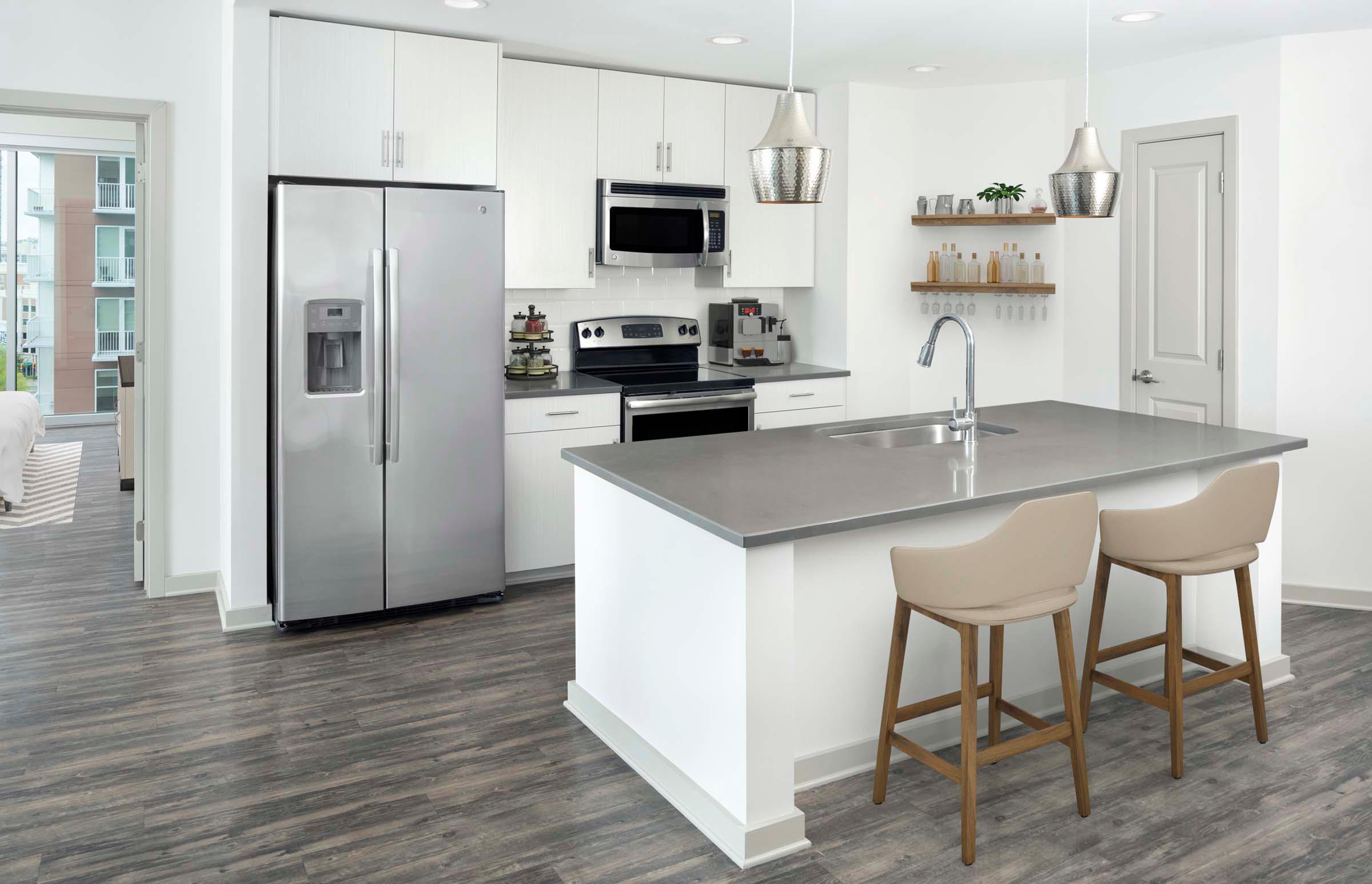 Two-bedroom kitchen with gray countertops, light cabinets, white backsplash and stainless steel appliances
