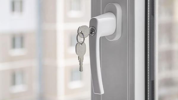 A set of small key in the lock of a white framed window