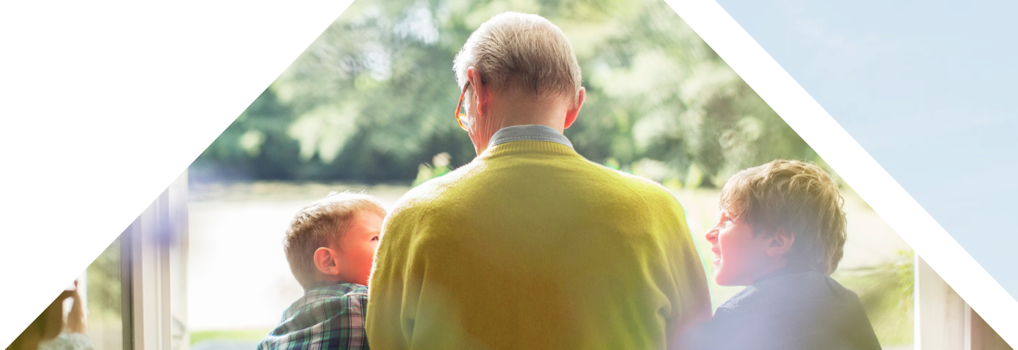 A grandfather sitting by the door to the backyard with his two young grandsons.