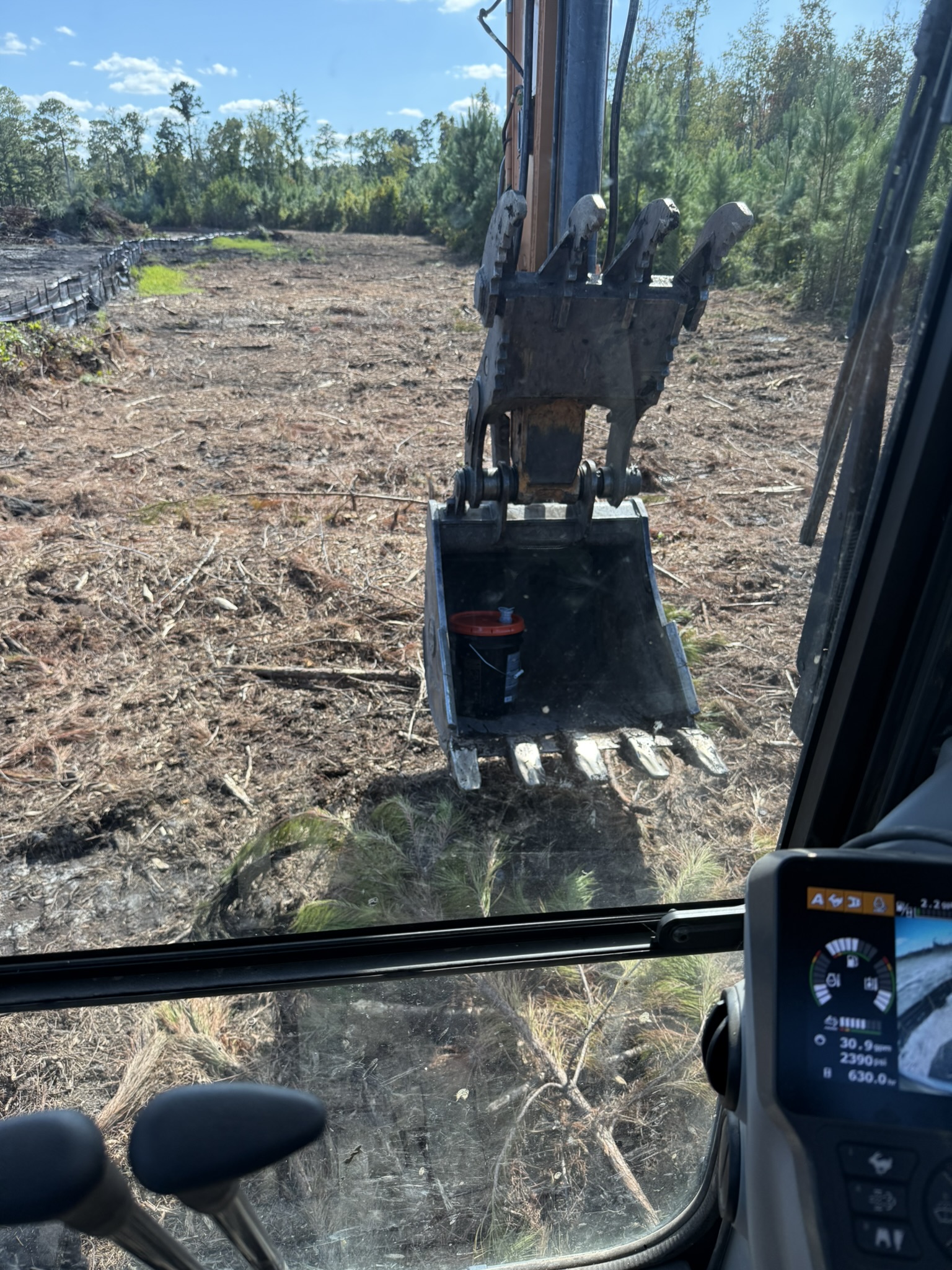 Photo from inside excavation equipment showing a cleared property area being graded and prepared for land improvement or site preparation.