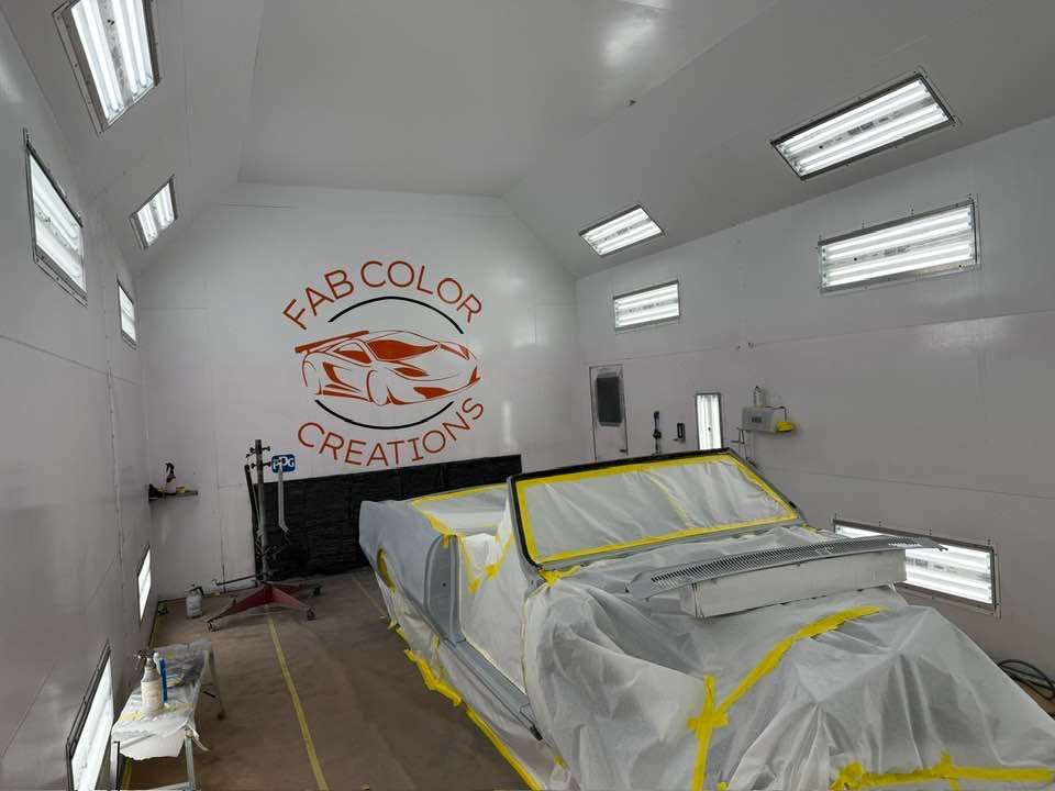 A classic convertible is covered with masking materials before painting. The controlled booth environment helps ensure smooth coverage, clean finishes, and high-quality automotive restoration results.