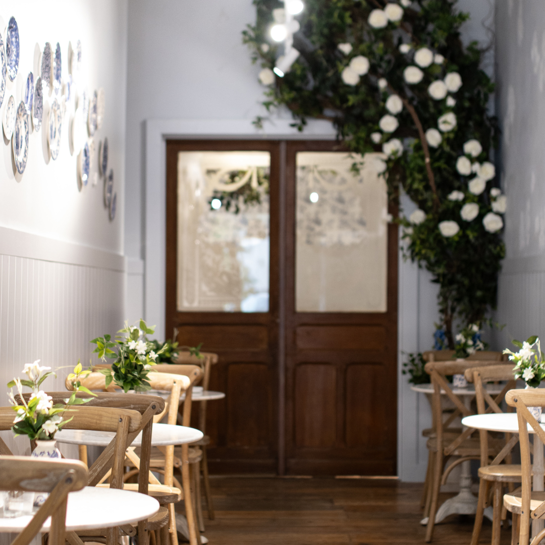 A cozy dining area inside maman Park Cities featuring natural light, wooden seating, marble café tab 