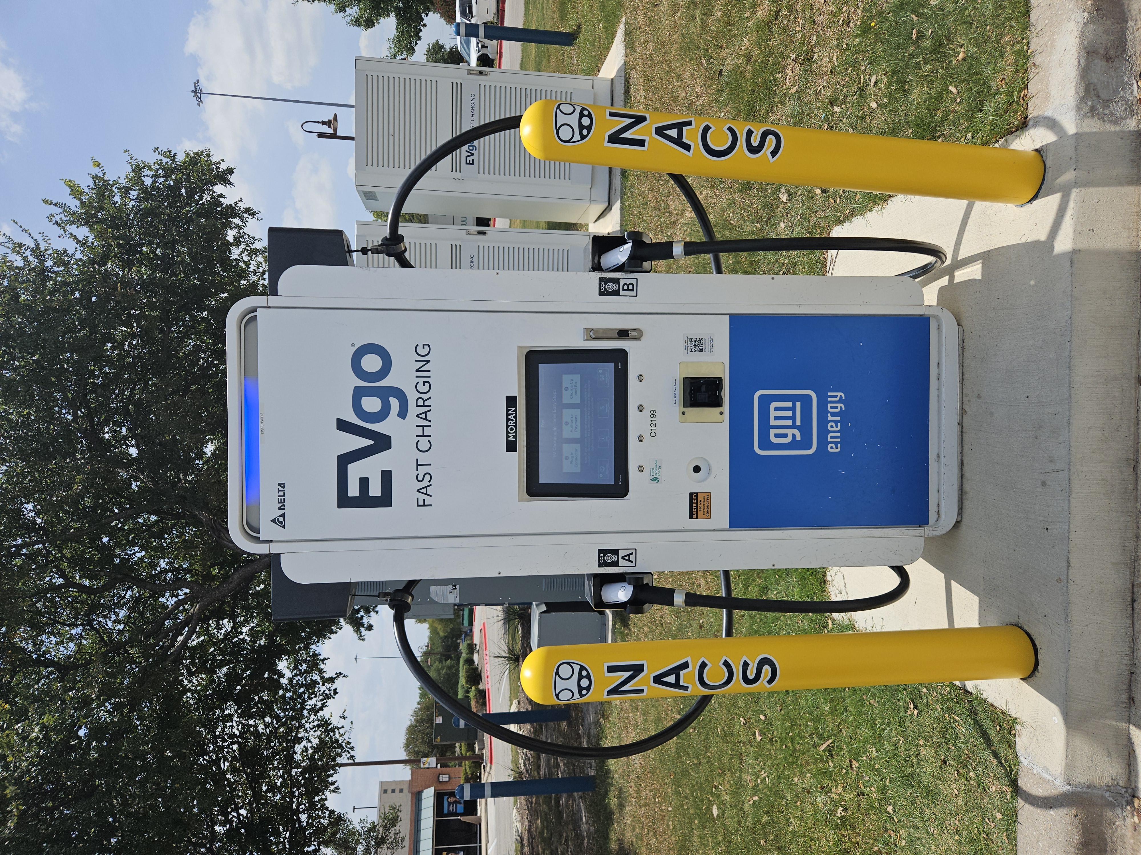 NACS EVgo fast charging unit installed in marked parking space at a public charging station, with EV 