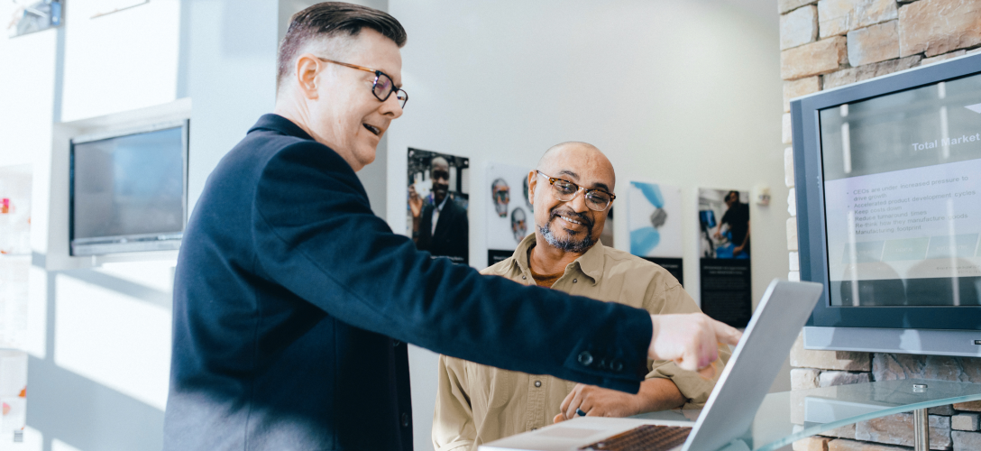 Two entrepreneurs pointing at a laptop screen during a meeting.