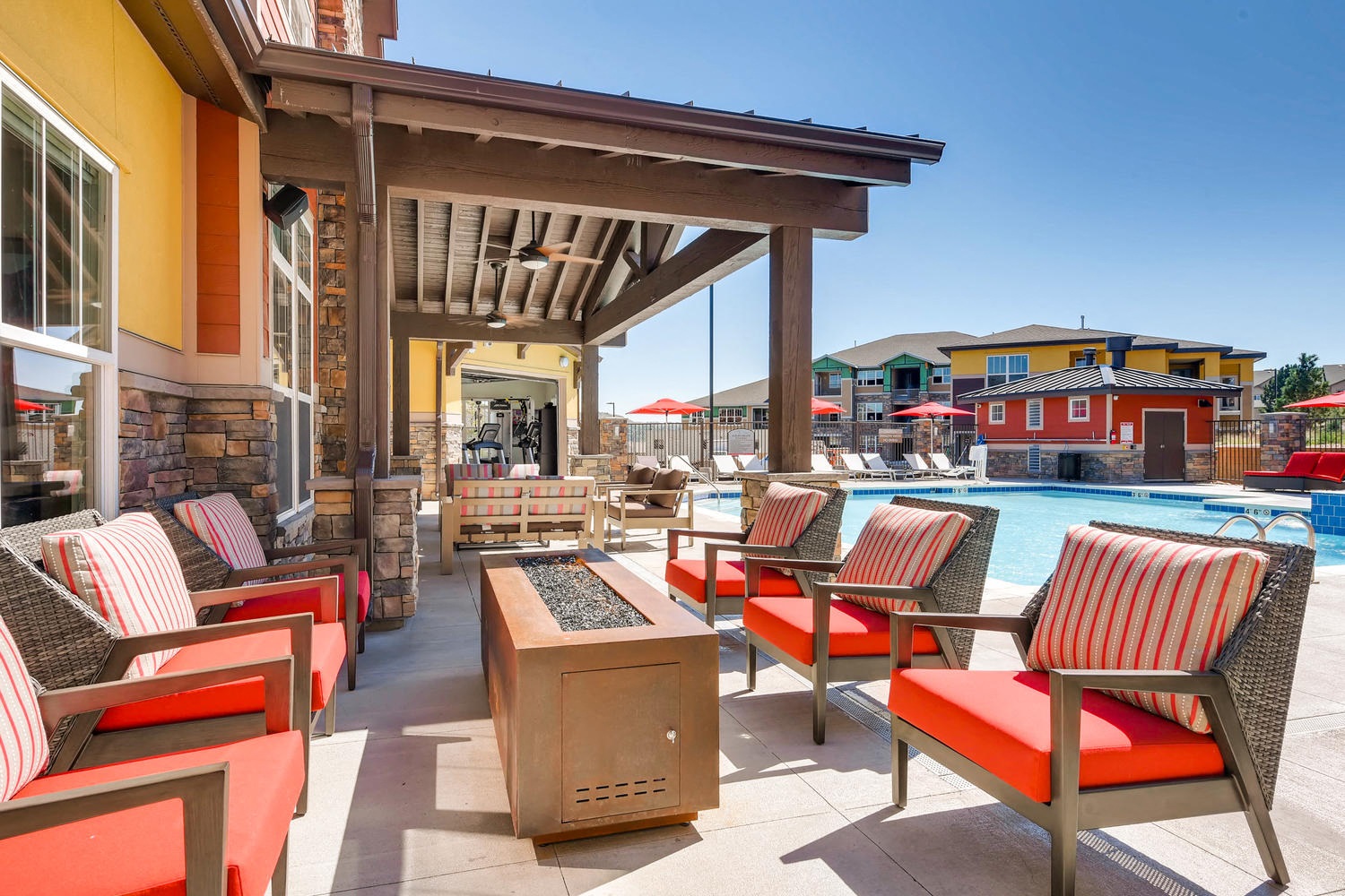 A patio with red and white striped chairs and a firepit.