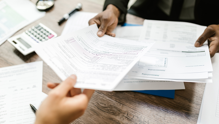 Close-up of an advisor passing a document to their client.