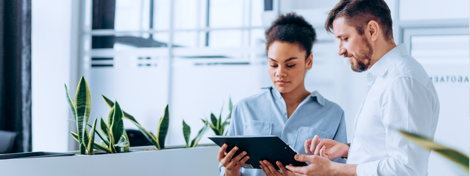 A man and a woman looking at a tablet in an office.