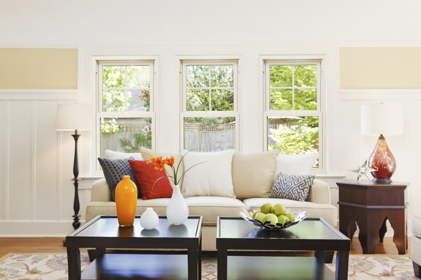 The EcoTek 1200 - 2200 Series Double Hung Windows in this living room provide abundant natural light and a classic style. Their clean lines and grid patterns complement the bright and colorful decor, creating a warm and inviting atmosphere that enhances the space's comfort.