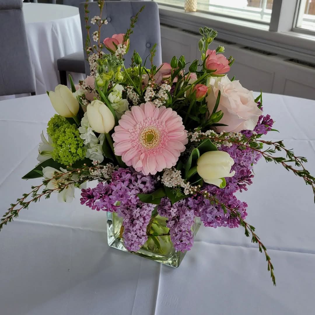 Table centerpiece for First Holy Communion, Huntington Yacht Club, Huntington, NY. Spring flowers, pastel floral color palette, lilac, tulips, butterfly ranunculus, mini gerbera daisy
