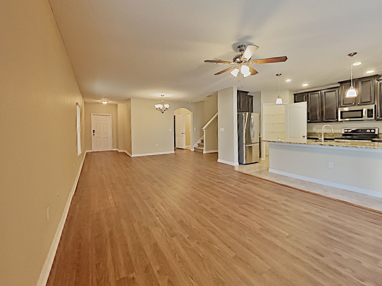 Spacious living area with modern kitchen and stainless steel appliances  at Invitation Homes Tampa.