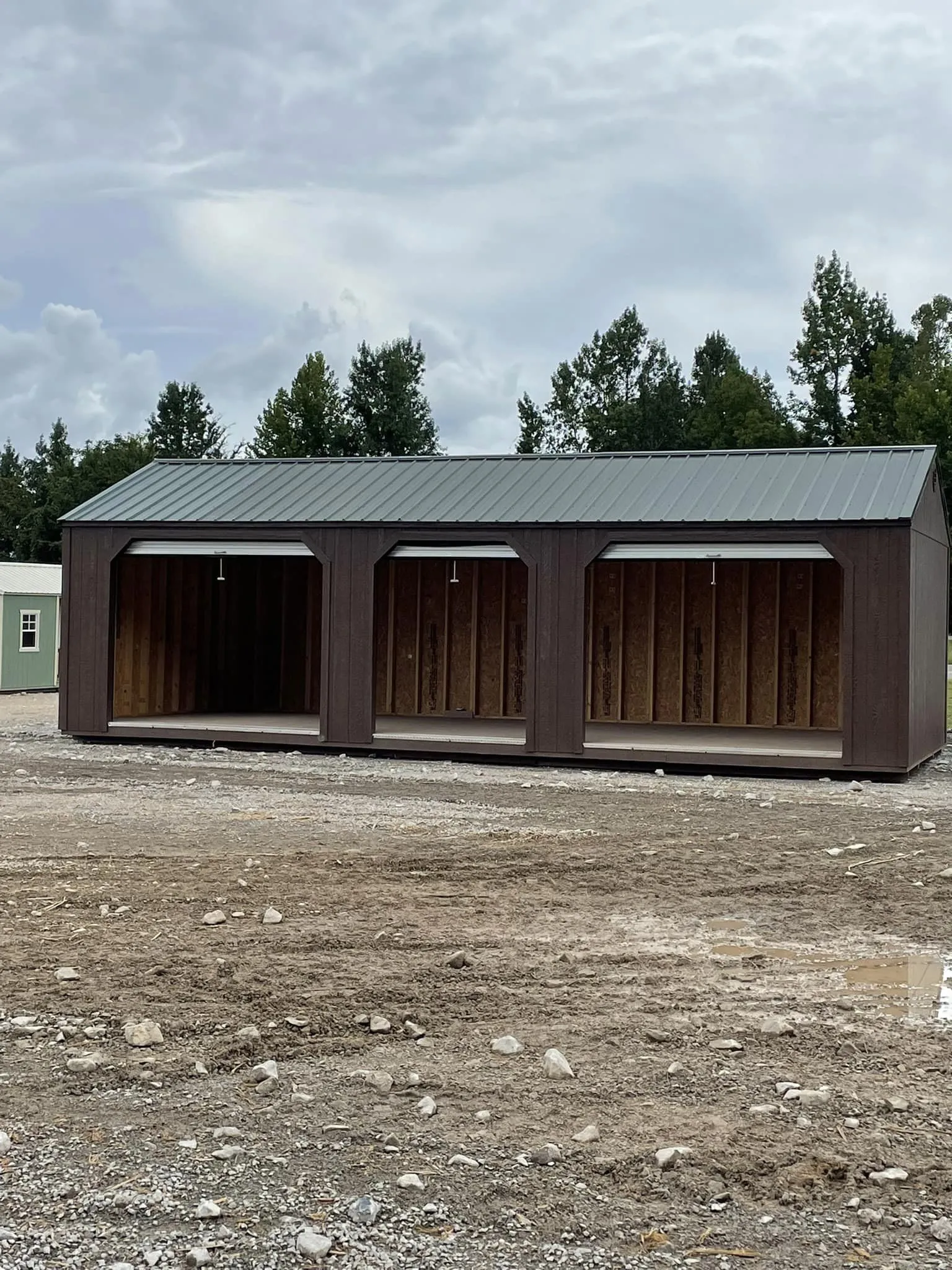 Large brown portable garage featuring three spacious open bays beneath durable metal roofing. Ideal for vehicle storage, equipment protection, workshops, or agricultural operations requiring flexible covered space.