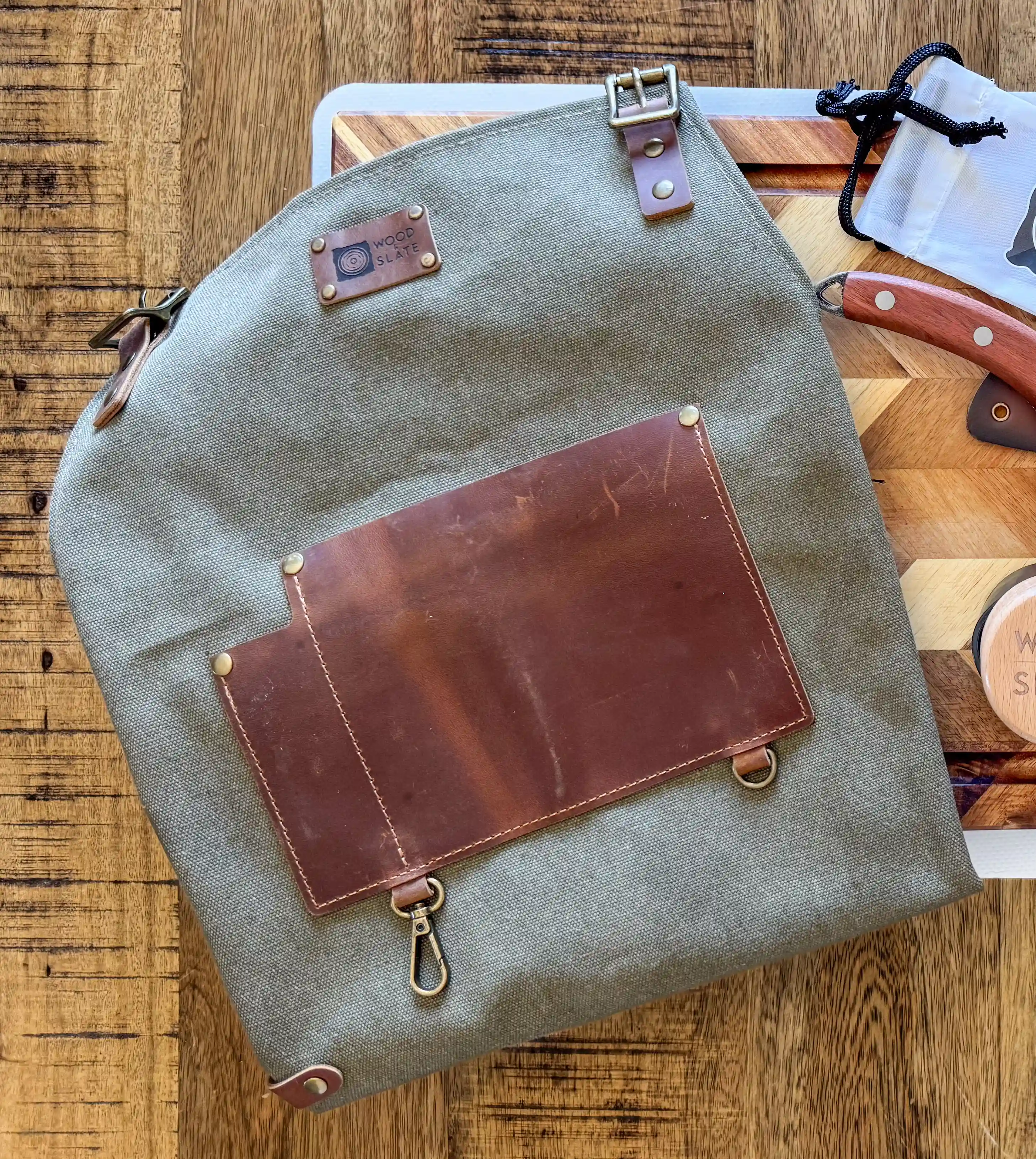 Choose Your Apron: Rugged Utility or Tactical Luxury
Whether you're flipping steaks, prepping garnishes, or carving up a brisket masterpiece, our aprons are built for serious performance—and serious style.
Crafted by Wood & Slate and made for makers, each apron is built to last, look great, and carry everything you need within arm's reach.
Canvas Apron (Tan or Grey)
A durable, everyday essential for cooks, grillers, and hands-on creators.
Features:
Available in Tan or Grey
Heavy-duty canvas body with brass grommets
Two deep front pockets + dedicated thermometer/pen holder
Reinforced leather accents
Embroidered Wood & Slate logo adds signature flair
Perfect for weekend warriors, BBQ hosts, or gift sets with cutting boards and accessories.