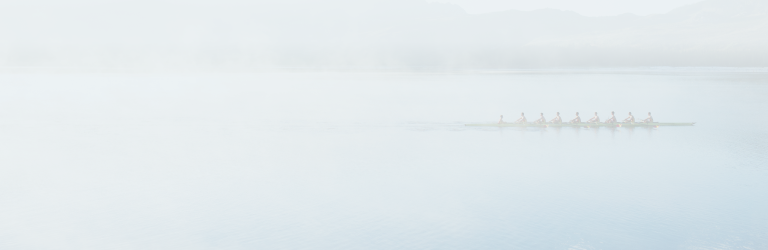 Une équipe d'aviron s'entraîne sur un lac.