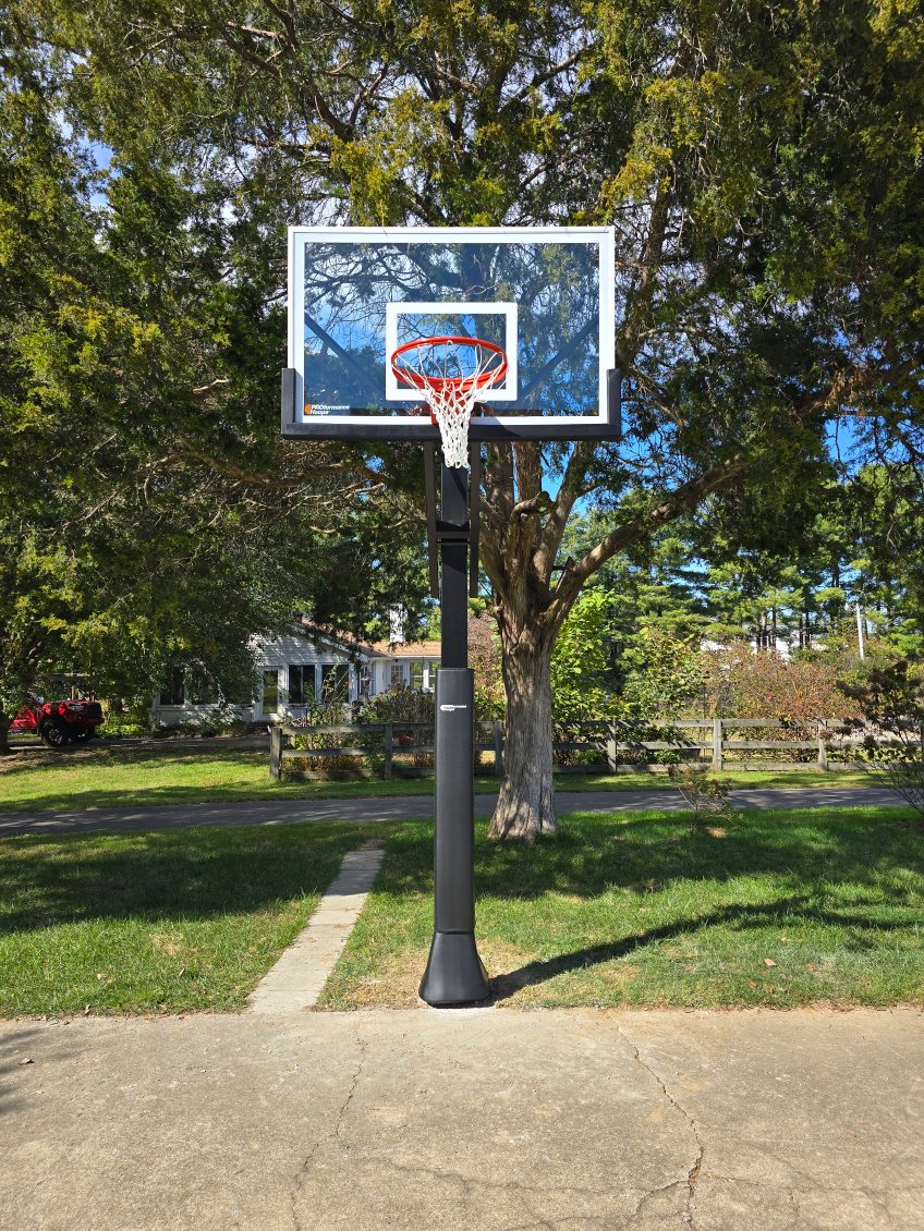 Adjustable in-ground basketball hoop on a concrete driveway.