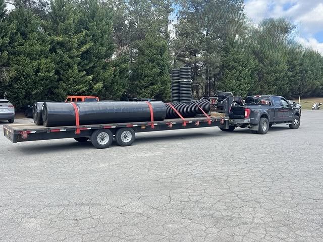 Large industrial pipes and fittings are securely strapped to a flatbed trailer, demonstrating safe f 