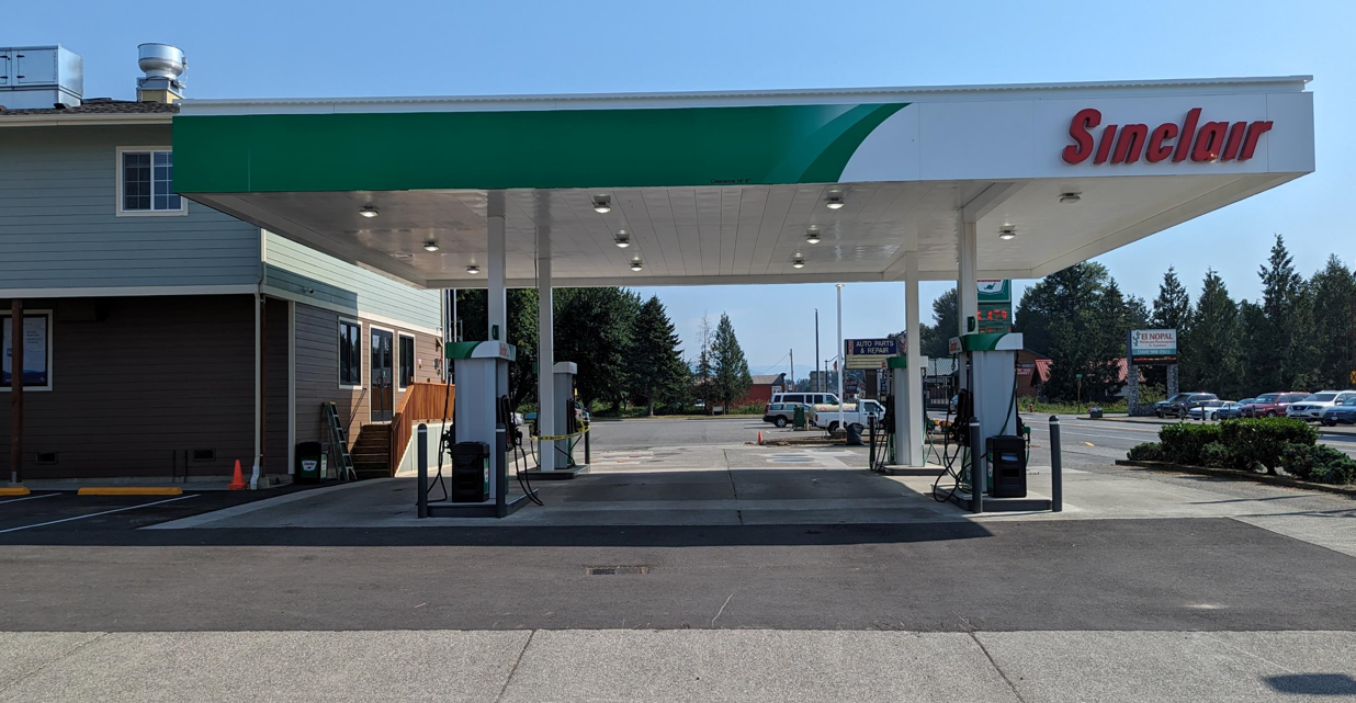 Gas station canopy and 4 pumps with Sinclair Wordmark.