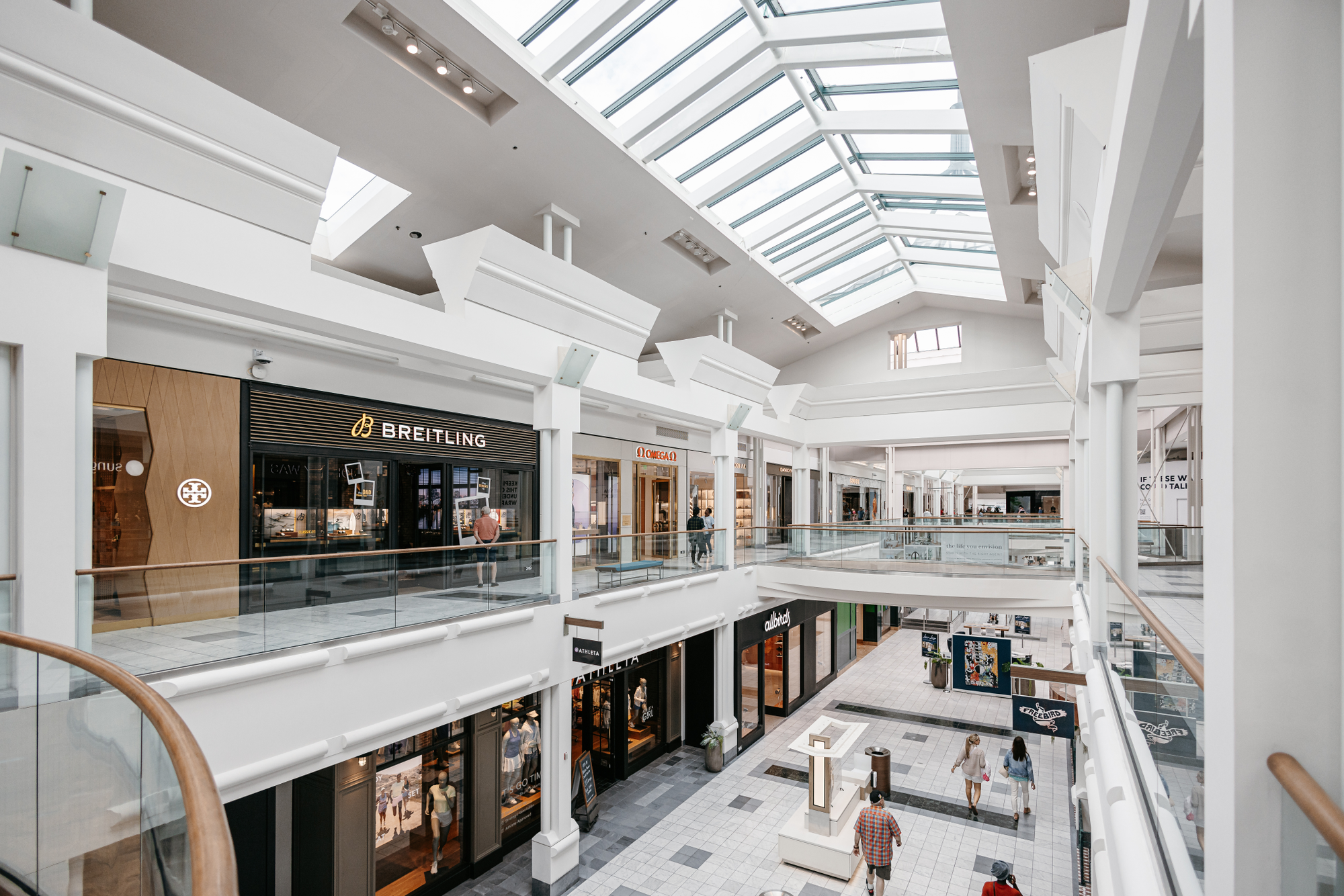Looking down luxury shopping wing, showing Brietling, OMEGA, Golden Goose, Saint Laurent, Gucci, Louis Vuitton, Dolce and Gabbana, Tiffany and Co.