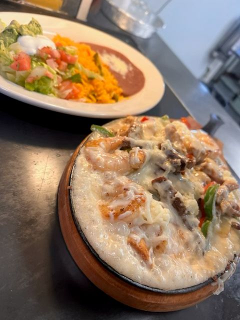 Shrimp, grilled steak, peppers, and melted cheese served with Mexican rice, refried beans, and a fresh side salad at Catramex Restaurant.