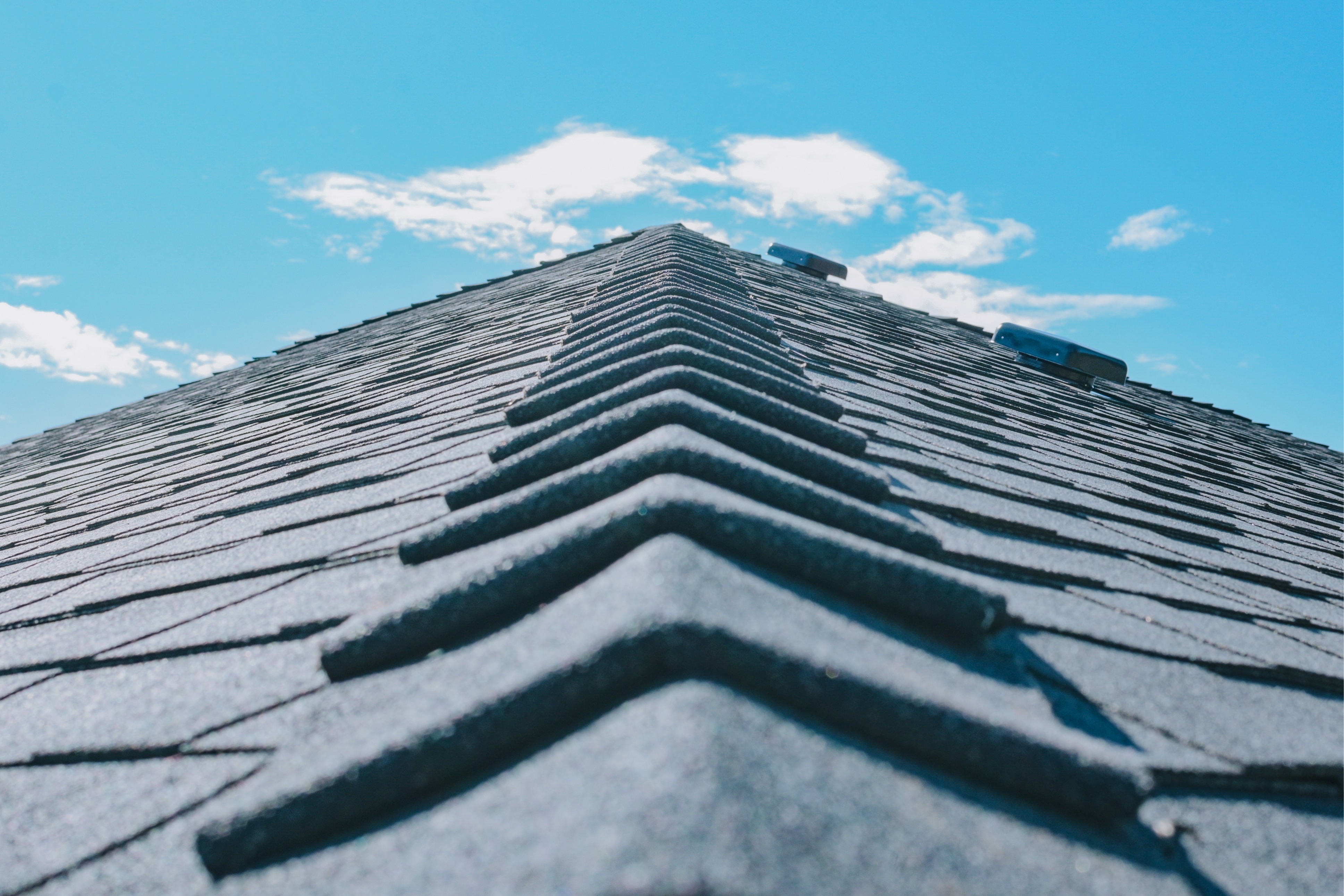 Finished ridge-cap shingles installed along the peak of an asphalt shingle roof. 