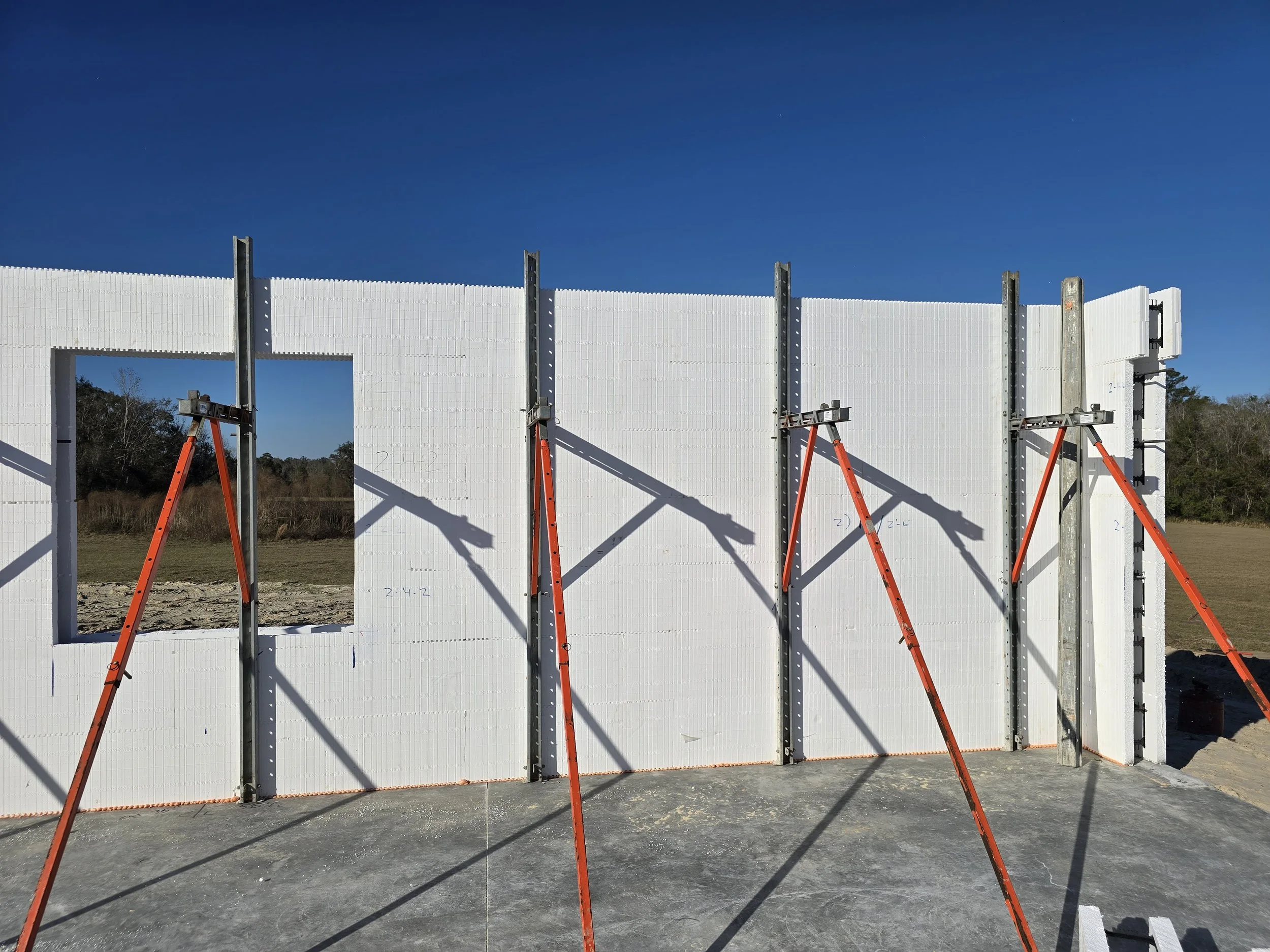 A construction site shows a building under construction with white Insulated Concrete Forms (ICFs) f 