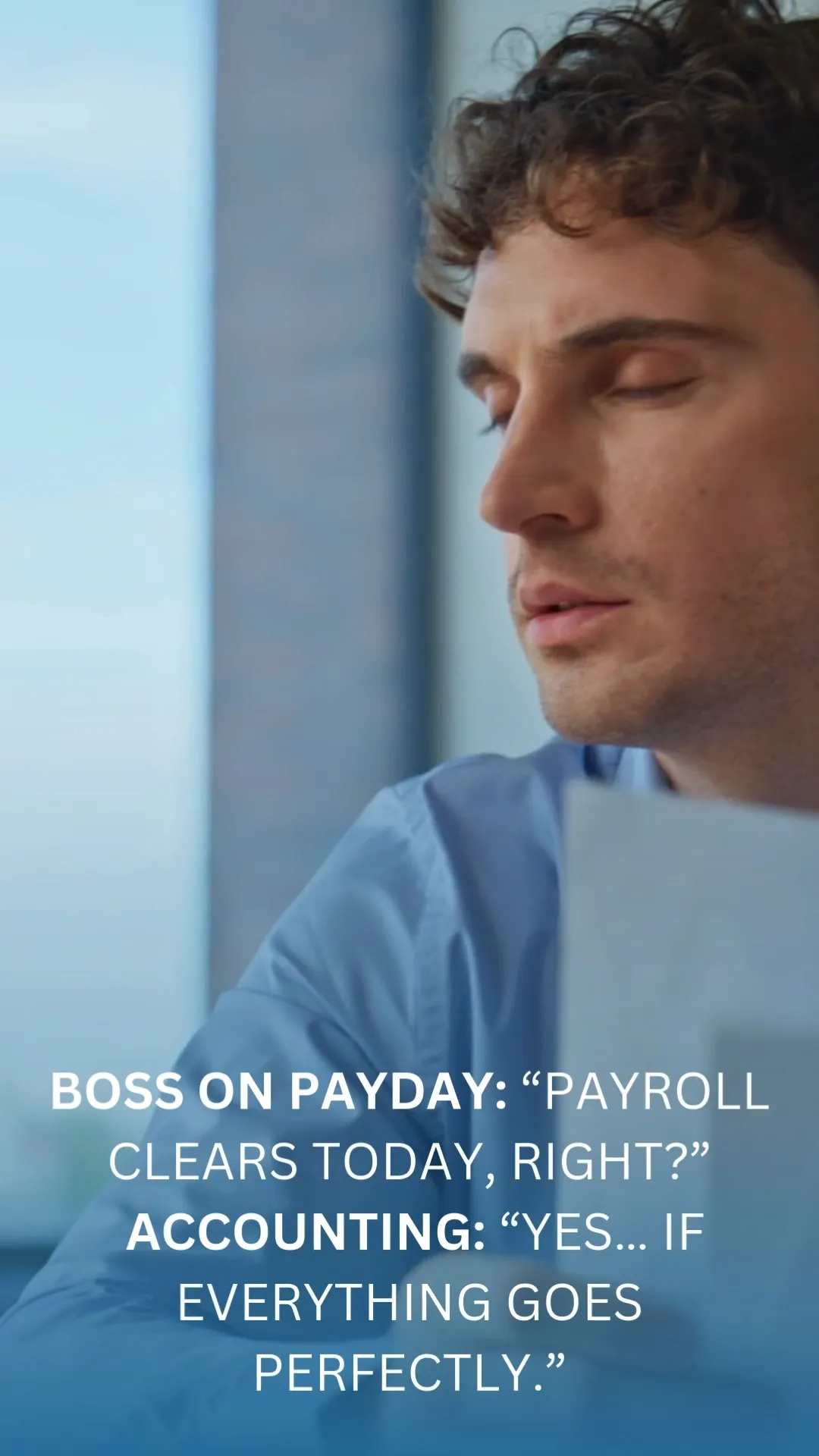 A close-up shot focuses on a man with curly brown hair and closed eyes, wearing a light blue collared shirt. He appears to be in an office setting, with a blurred background suggesting a window and office partitions. Text overlays the image with a conversation about payroll: "BOSS ON PAYDAY: 'PAYROLL CLEARS TODAY, RIGHT?' ACCOUNTING: 'YES... IF EVERYTHING GOES PERFECTLY.'"