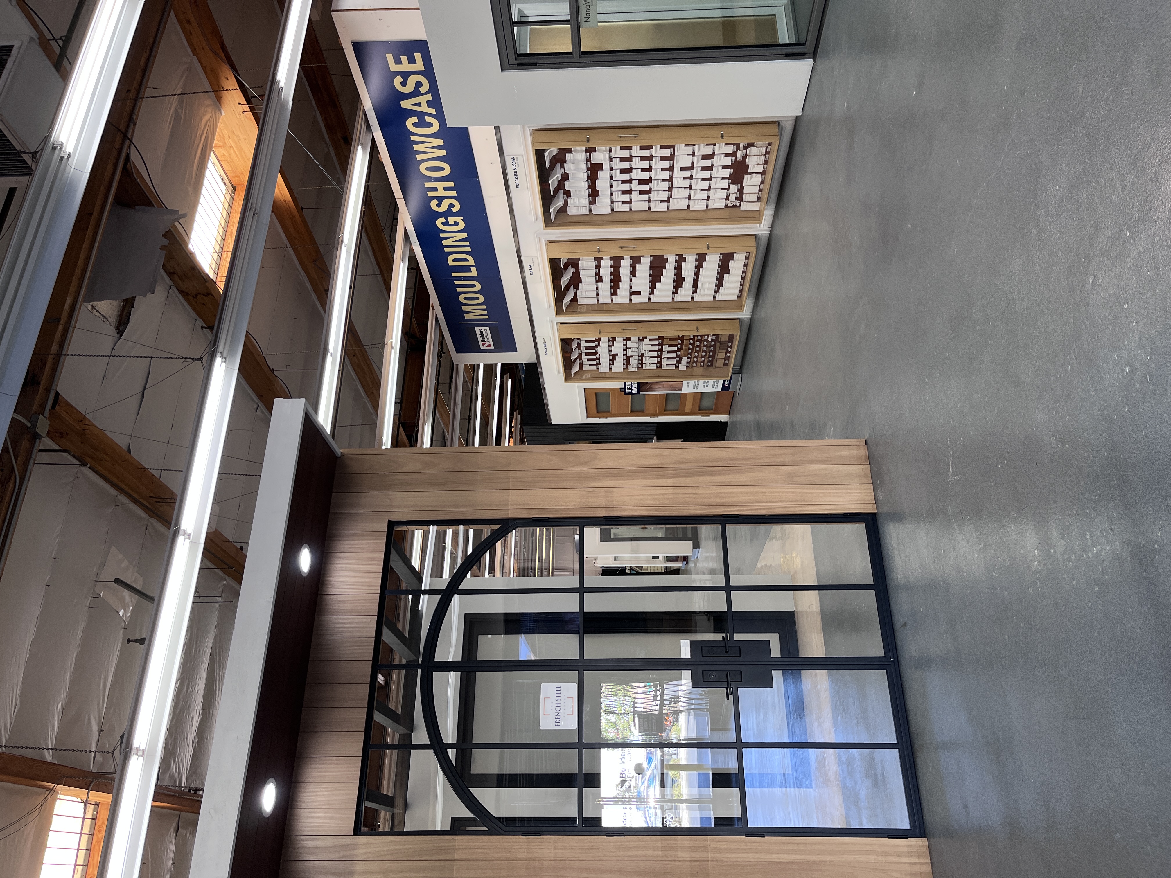 Interior showroom entrance at Builders FirstSource Thousand Oaks, CA, featuring a French Steel door display and the Moulding Showcase wall in the background.