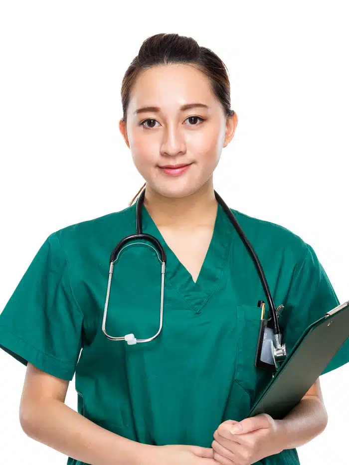 A medium shot of a young East Asian woman dressed in green medical scrubs, wearing a stethoscope around her neck, and holding a clipboard. She has her hair pulled back in a bun and is looking directly at the camera with a slight smile. The background is plain white.