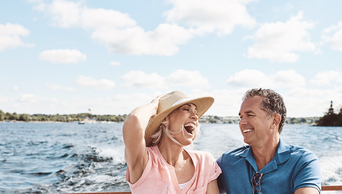 A couple laughing and smiling together during a boat ride on a lake.
