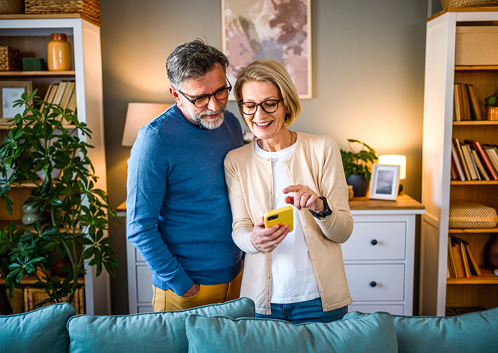A couple looking at their phone in their warmly lit living room.