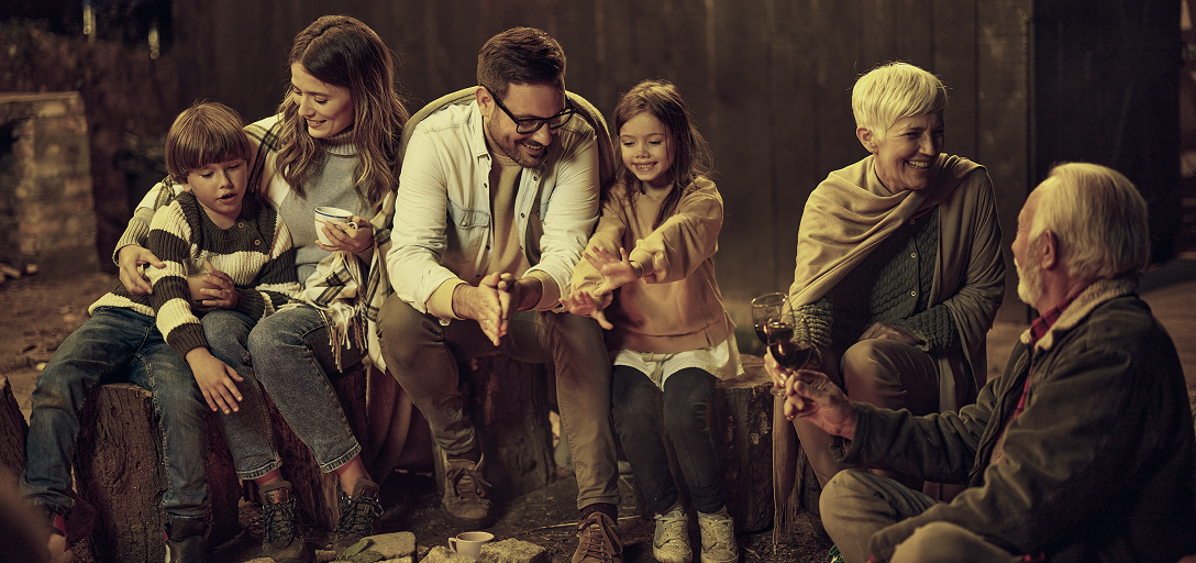 A multigenerational family gathered around a fire.