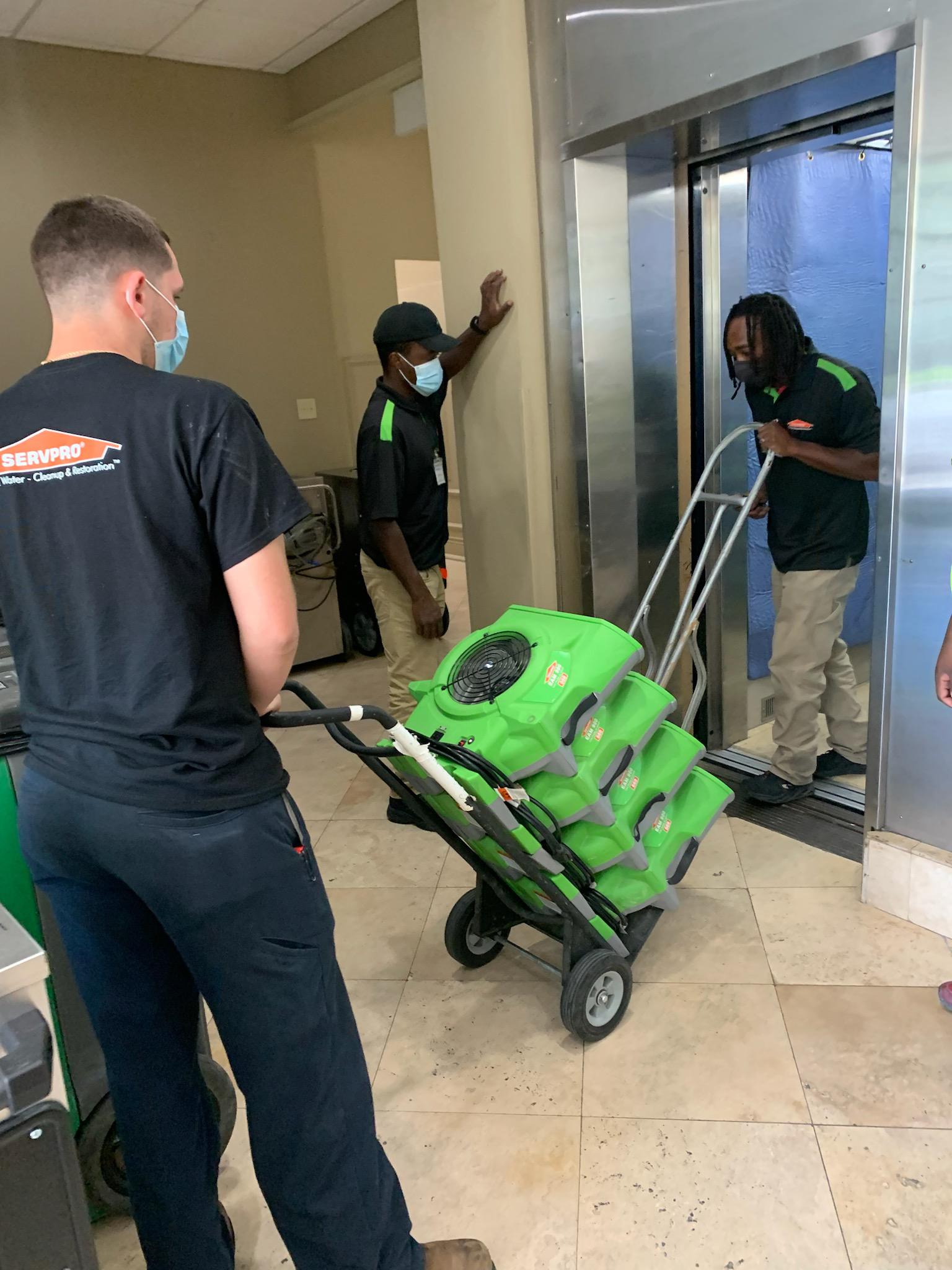 SERVPRO crew bringing floor dryers to the flooded building.